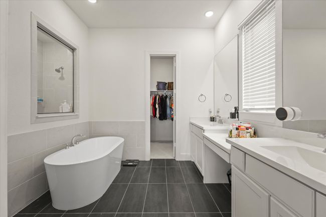Full bathroom featuring two vanities, a freestanding bath, tile patterned floors, tile walls, and a walk in closet | Image 15