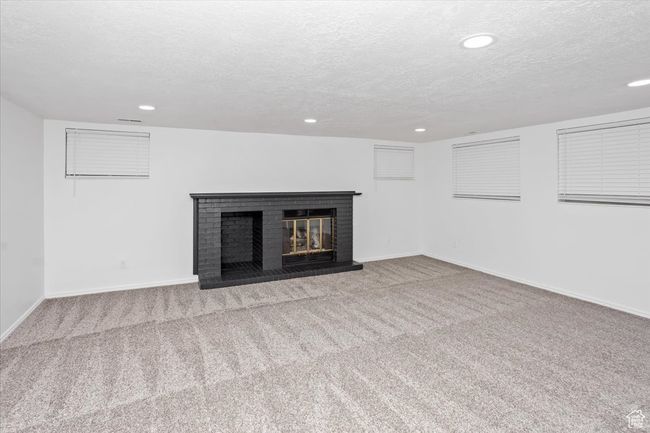 Unfurnished living room with baseboards, carpet floors, recessed lighting, and a brick fireplace | Image 27
