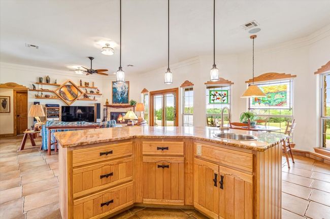 Kitchen featuring a sink, open floor plan, light stone counters, light tile patterned floors, and crown molding | Image 16