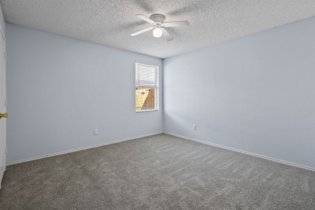 Carpeted empty room featuring ceiling fan and a textured ceiling | Image 14