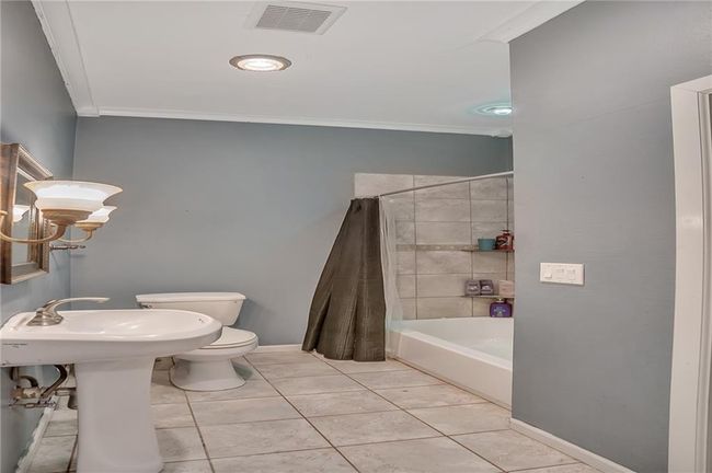 Full bath with crown molding, tile patterned floors, baseboards, toilet, and visible vents | Image 12