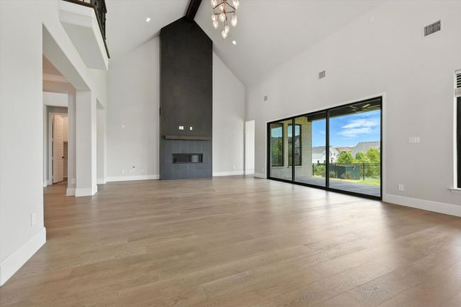 Unfurnished living room featuring high vaulted ceiling, light wood-type flooring, beam ceiling, and a tile fireplace | Image 13