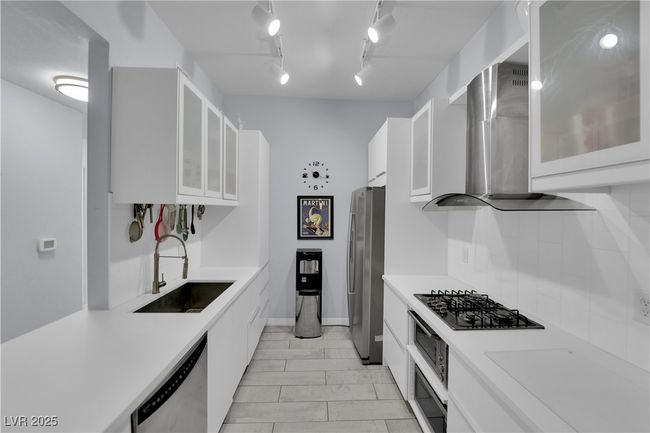 Kitchen with appliances with stainless steel finishes, white cabinets, light countertops, and wall chimney range hood | Image 16