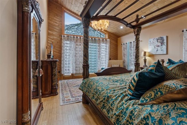 Bedroom with lofted ceiling, wooden ceiling, hardwood / wood-style floors, a notable chandelier, and recessed lighting | Image 58