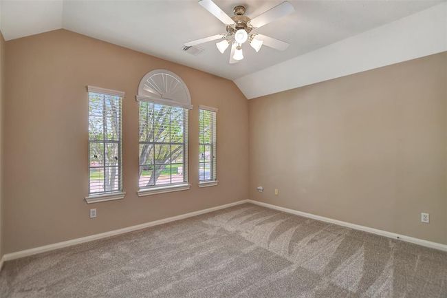 This room features neutral-toned walls, a ceiling fan, and a large window with an arched accent, providing ample natural light and a spacious feel. Ideal for a bedroom or home office. | Image 39
