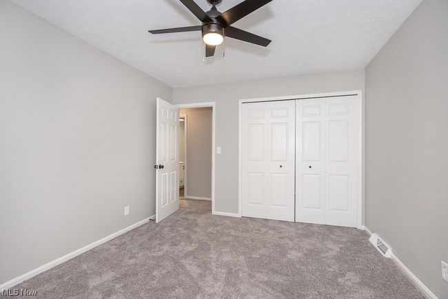 Unfurnished bedroom with light colored carpet, ceiling fan, and a closet | Image 17