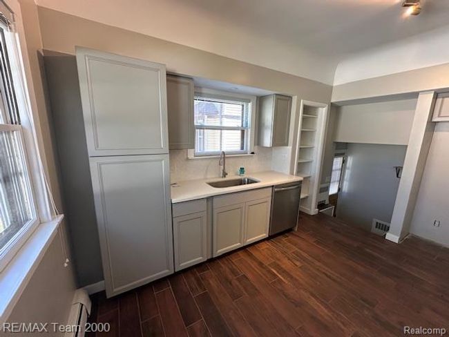 Kitchen with dark wood-style flooring, dishwasher, a baseboard heating unit, gray cabinets, and decorative backsplash | Image 17