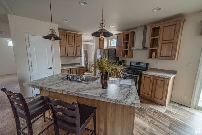 Kitchen with a sink, gas stove, wall chimney range hood, open shelves, and a breakfast bar | Image 45