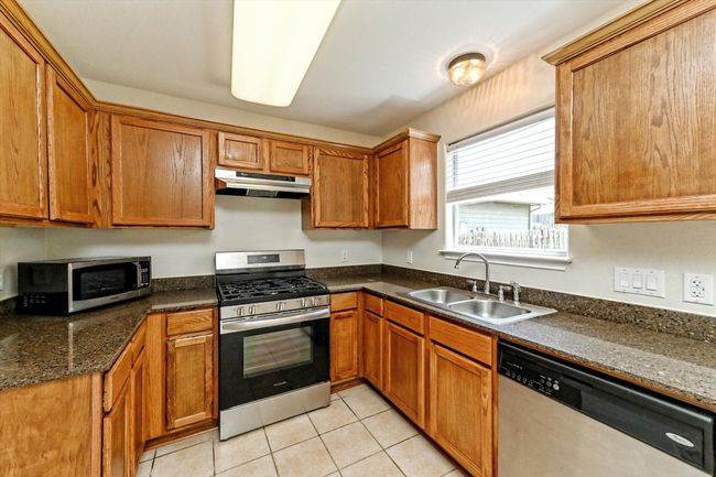 Stainless steel appliances, tile floors, under cabinet range hood, and Silestone countertops. | Image 12