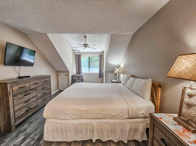 Bedroom with a textured ceiling, dark wood finished floors, ceiling fan, and lofted ceiling | Image 21