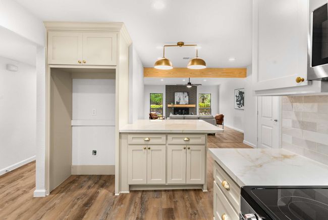 Kitchen featuring stainless steel microwave, wood like finished floors, porcelain countertops, a peninsula, and recessed lighting | Image 10