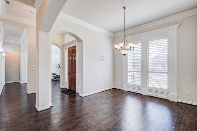 Spare room with crown molding, dark hardwood / wood-style flooring, and an inviting chandelier | Image 7