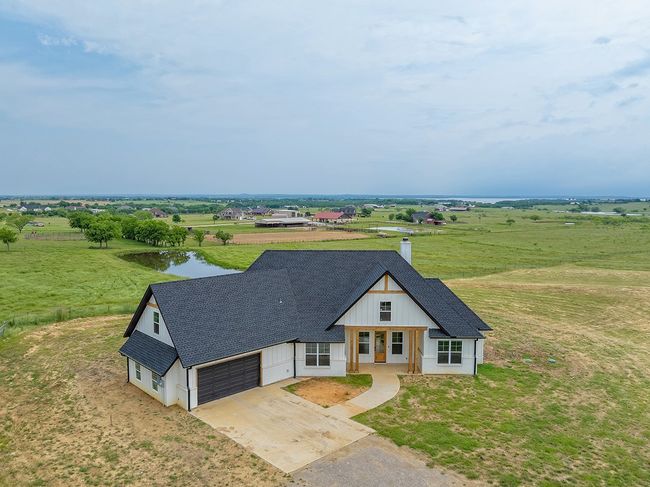 View of front of property with concrete driveway, roof with shingles, a chimney, and a rural view | Image 37