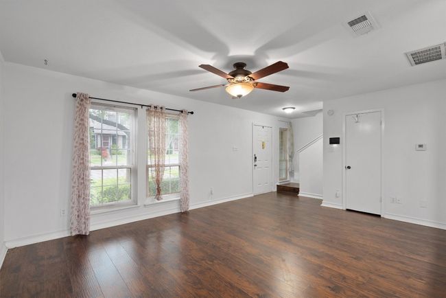 Unfurnished living room with a ceiling fan and dark wood-style flooring | Image 6