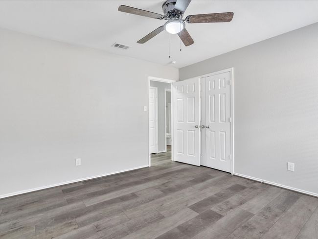 Unfurnished bedroom featuring wood finished floors, baseboards, a ceiling fan, and a closet | Image 14