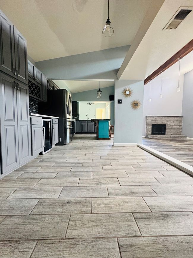 Bar with wine cooler, stainless steel fridge, white cabinets, light stone countertops, and backsplash | Image 8