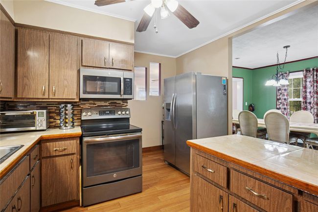 Kitchen with crown molding, light wood-style flooring, appliances with stainless steel finishes, and a toaster | Image 10