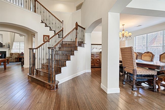Stairway with a chandelier, a high ceiling, wood finished floors, and baseboards | Image 24