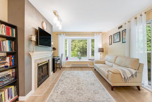 Living room featuring a baseboard radiator, a premium fireplace, and wood finished floors | Image 17