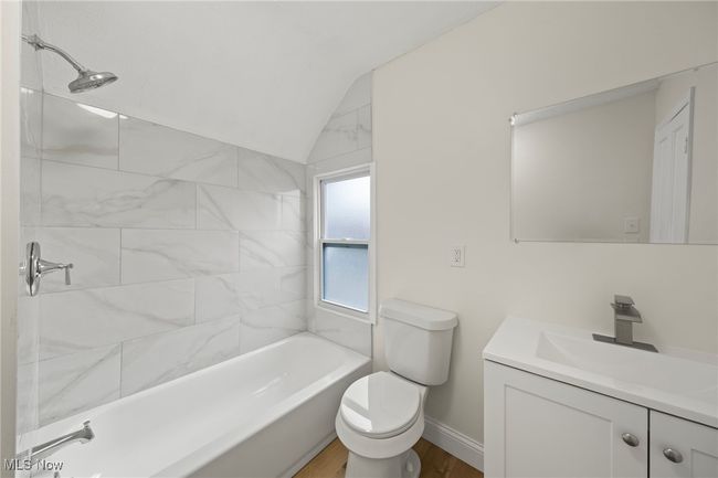 Full bathroom with hardwood / wood-style floors, vanity, tiled shower / bath, vaulted ceiling, and toilet | Image 20
