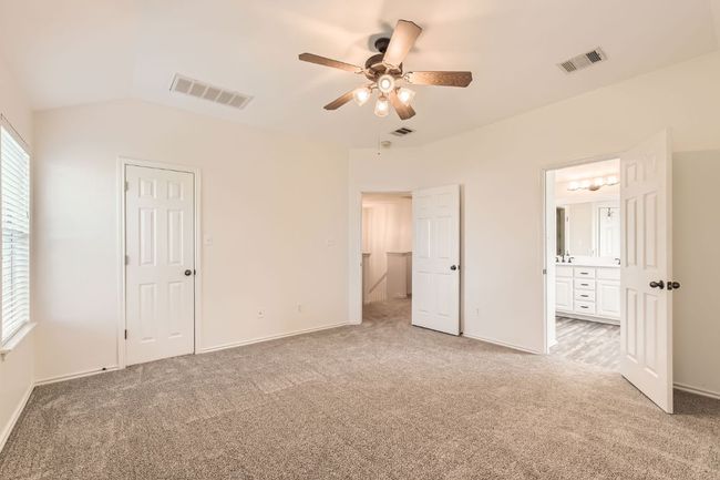 Primary bedroom upstairs with light carpet, vaulted ceiling, ensuite bath, and ceiling fan | Image 20