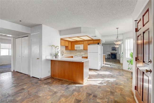 Kitchen with a sink, baseboards, white appliances, and a peninsula | Image 6