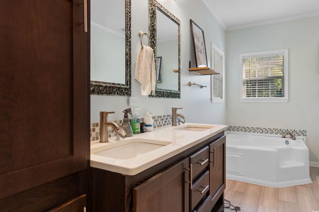 Full bathroom with crown molding, a bath, double vanity, and wood finished floors | Image 17