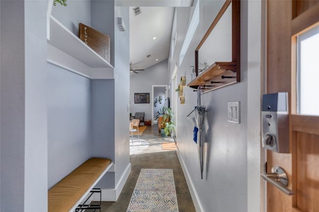 Hall featuring finished concrete floors, baseboards, healthy amount of natural light, and a towering ceiling | Image 7