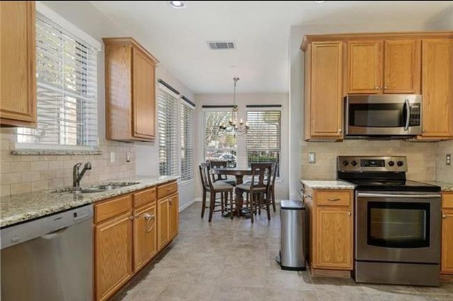 Kitchen with appliances with stainless steel finishes, backsplash, light tile flooring, and an inviting chandelier | Image 6