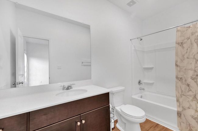 Full bathroom with visible vents, toilet, wood finished floors, vanity, and shower / bath combination with curtain | Image 15