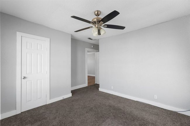 Unfurnished bedroom with dark colored carpet and a ceiling fan | Image 14