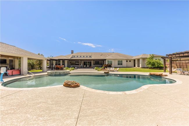 View of swimming pool featuring a patio, a pergola, and a pool with connected hot tub | Image 21
