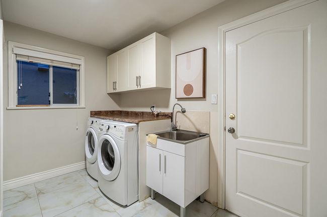 Laundry room with independent washer and dryer, light marble finish flooring, cabinet space, and baseboards | Image 25