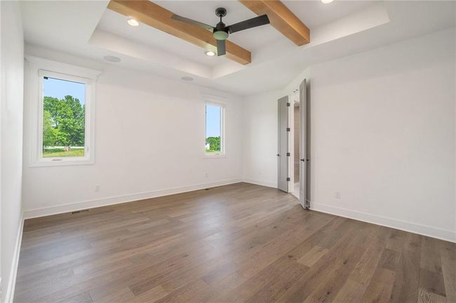 Empty room featuring healthy amount of natural light, wood finished floors, ceiling fan, recessed lighting, and a tray ceiling | Image 32