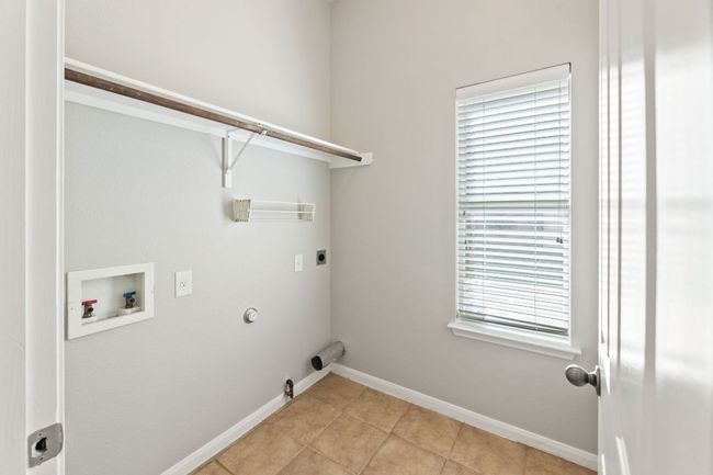 Laundry area featuring hookup for a gas dryer, washer hookup, light tile patterned flooring, and electric dryer hookup | Image 11