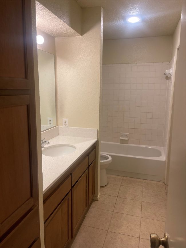 Full bath with a textured ceiling, vanity, tile patterned flooring, shower / tub combination, and a textured wall | Image 10