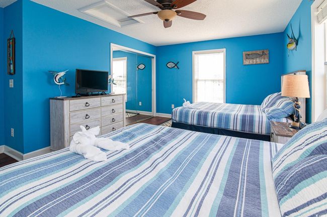 Bedroom featuring a textured ceiling, baseboards, wood finished floors, attic access, and a ceiling fan | Image 35