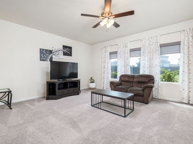 Carpeted living area with ceiling fan and baseboards | Image 5