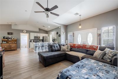 Living room with light wood-type flooring, vaulted ceiling, and ceiling fan | Image 3