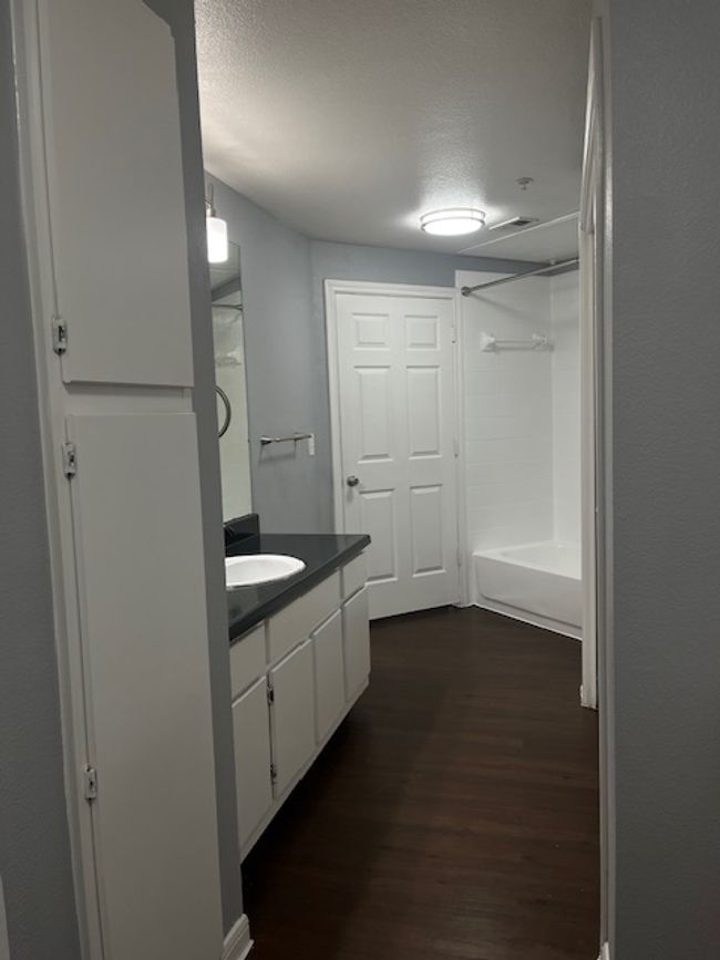 Bathroom with shower / bathing tub combination, wood finished floors, a textured ceiling, and vanity | Image 17