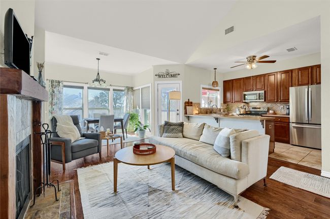 Living room featuring a fireplace, ceiling fan, light wood-style flooring, a chandelier, and high vaulted ceiling | Image 6