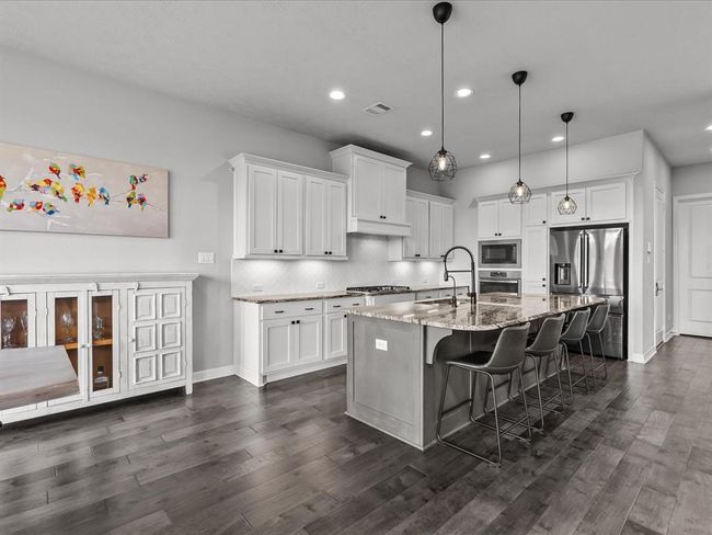 Chef's eat-in island kitchen features 42" cabinets with crown molding, under cabinet lighting, designer backsplash, stainless steel appliances and legthy countertops | Image 12