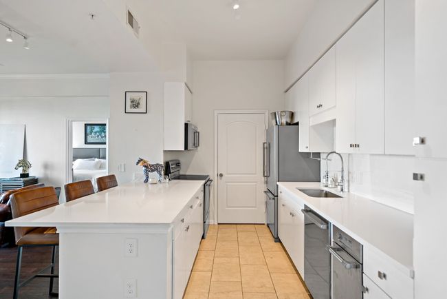 Kitchen with a breakfast bar area, a peninsula, appliances with stainless steel finishes, and a sink | Image 8