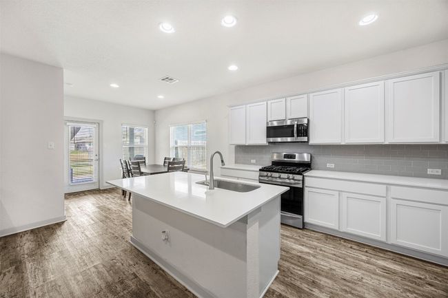 The heart of the home, this open-concept kitchen includes a large island with a sink, perfect for meal prep and casual dining, all overlooking the dining and living areas. | Image 12
