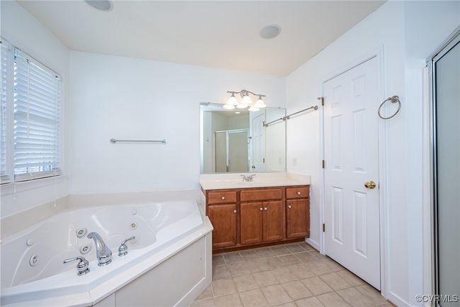 Full bathroom with a shower stall, vanity, a tub with jets, tile patterned floors, and plenty of natural light | Image 22