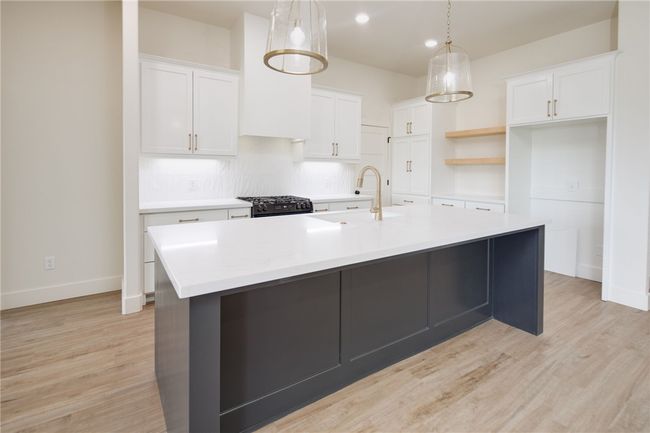 Kitchen featuring a sink, a kitchen island with sink, white cabinetry, light countertops, and recessed lighting | Image 8