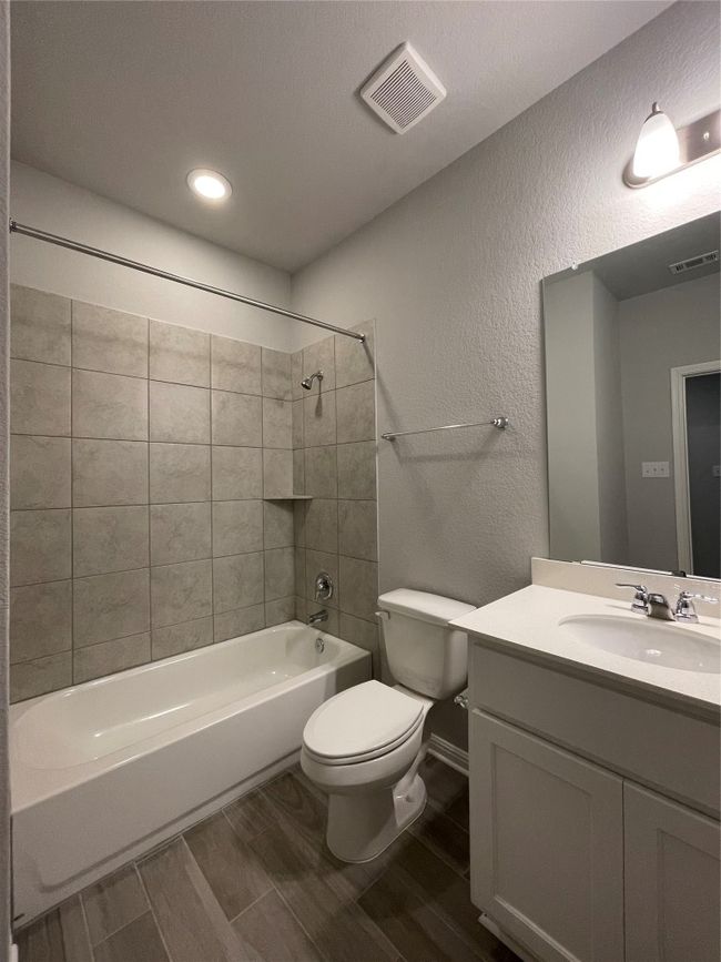 Full bathroom with a textured wall, vanity, wood tiled floors, shower / washtub combination, and recessed lighting | Image 10
