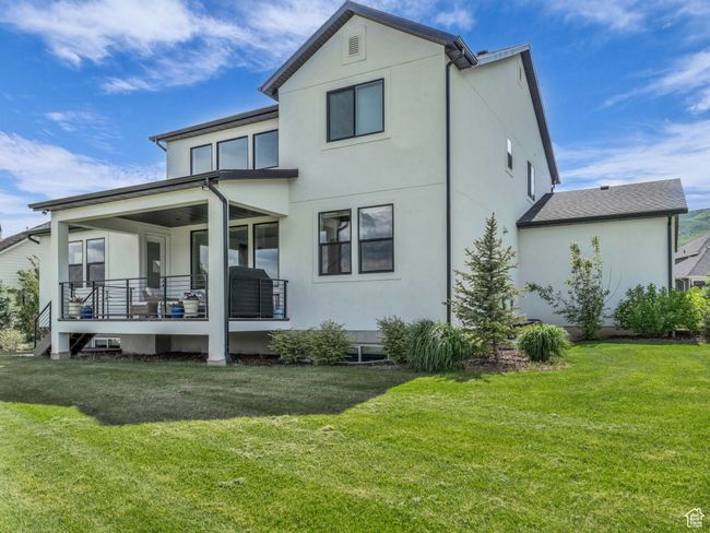 Rear view of property featuring stucco siding, a yard, and covered porch | Image 48