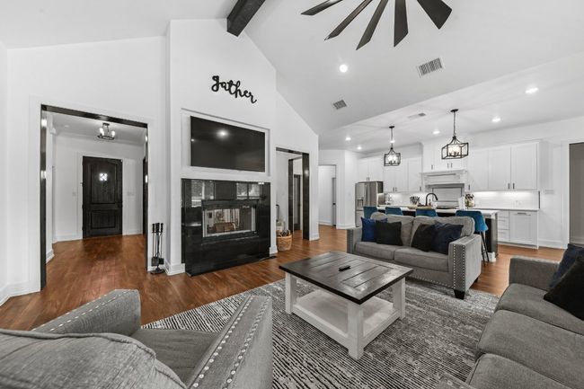 Living room with a multi sided fireplace, high vaulted ceiling, visible vents, and recessed lighting | Image 13