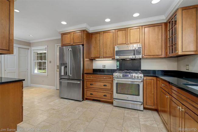 Kitchen with brown cabinets, ornamental molding, appliances with stainless steel finishes, glass insert cabinets, and recessed lighting | Image 9